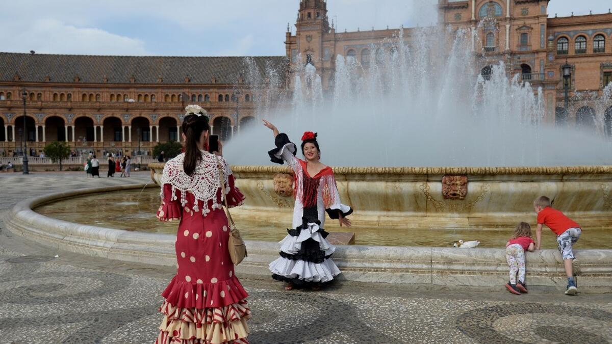 Tourists in traditional Sevillian dresses take photos at the Plaza de Espana square during the "Feria de Abril" (April Fair) festival in Seville on May 6, 2019. CRISTINA QUICLER / AFP
