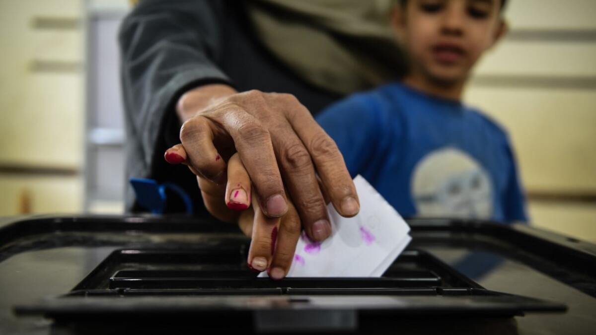 An man Egyptian casts his ballot with a child at a polling station during the third day of a referendum on constitutional amendments, at a school in shamma village in the northern Nile delta province of Menoufia, on April 22, 2019.  Mohamed el-Shahed / AFP